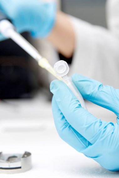 Close up of lab researchers hand operating a pipette