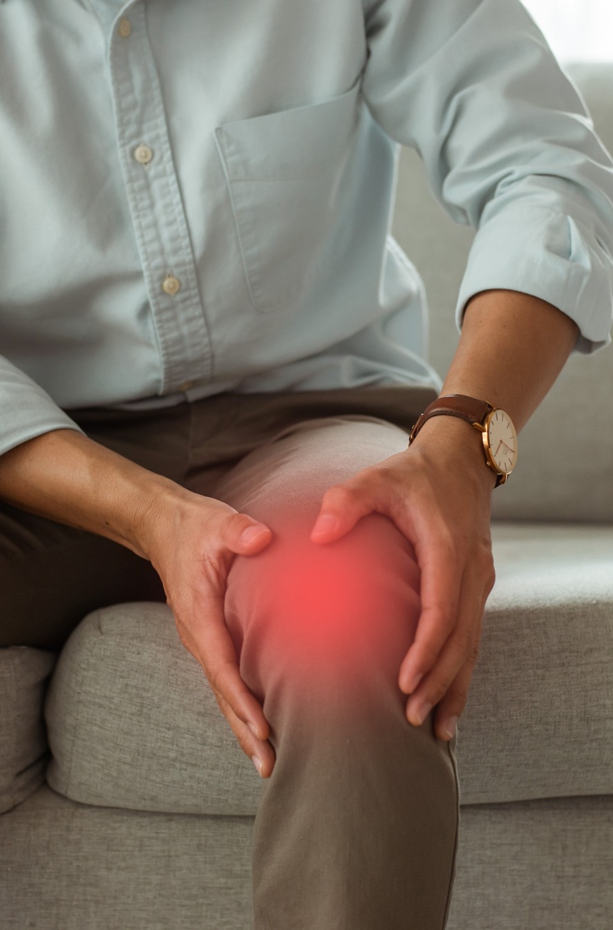 Man clutching at one knee, red overlay indicates pain